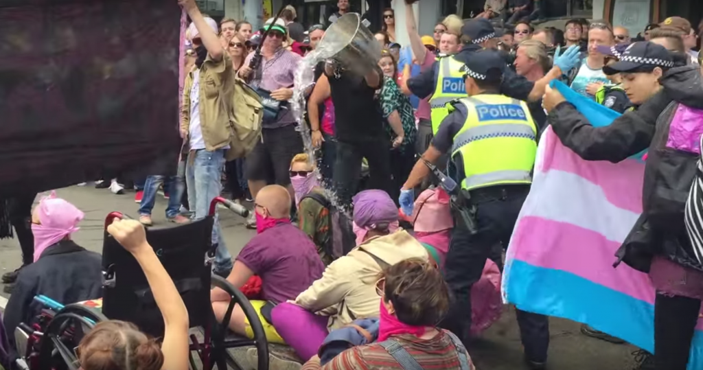 Queer and trans activists having buckets of water thrown at them from the crowd