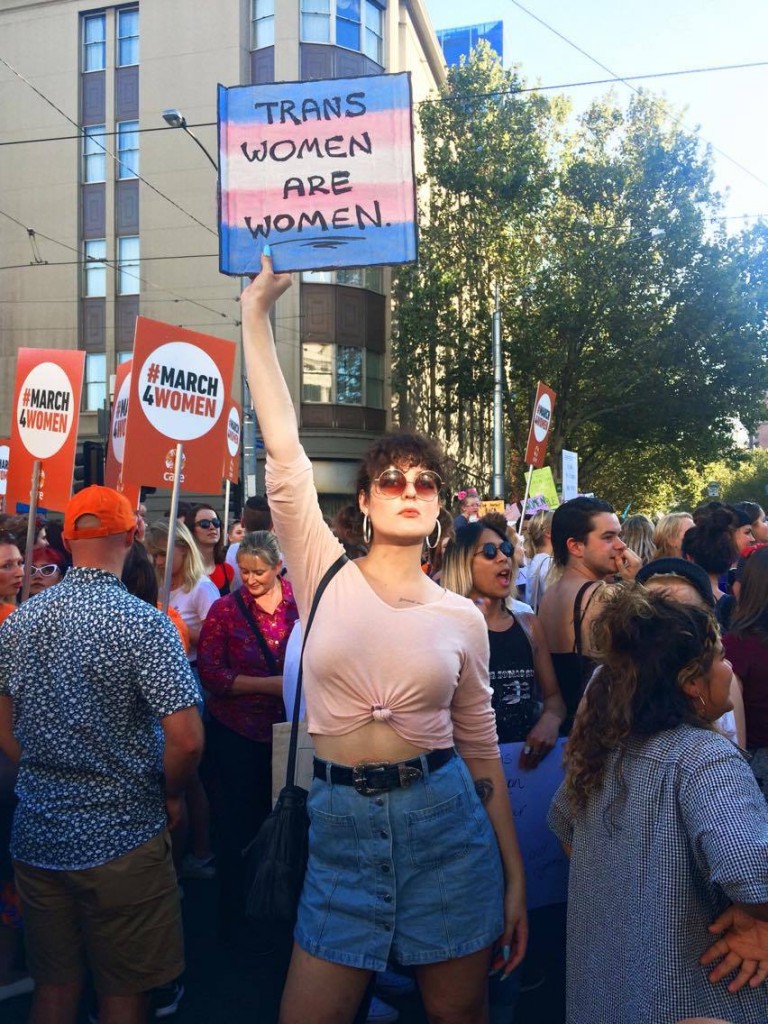Lana Faye holding a 'trans women are women' sign to TERFs