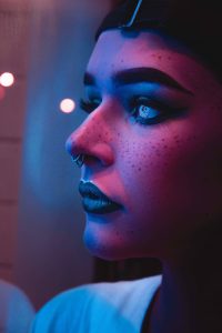 Photo of woman with black lipsticks and nose piercings captured inside dim light room