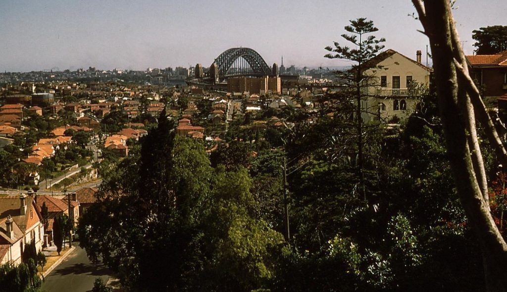An image of the Sydney Harbour Bridge from the north, with housing and trees in the foreground.