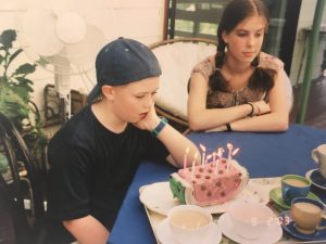 Person in front of a birthday cake wearing a blue hat