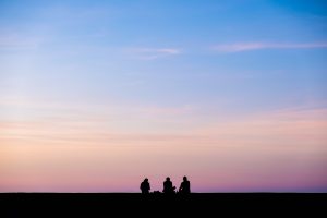 Silhouette photography of three people in front of a sunset