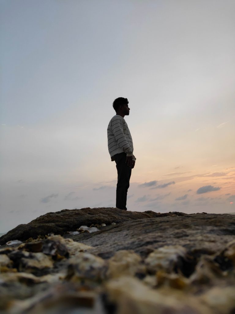 A person stands on some rocks in silhouette