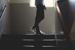 a person stands at the top of a staircase. The person is visible from the waist down.