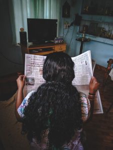 Person with long curly hair reading the newspaper