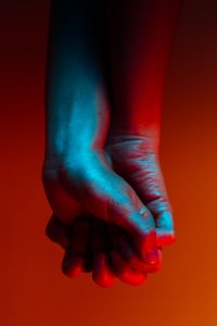 two hands clasped together in red and blue light