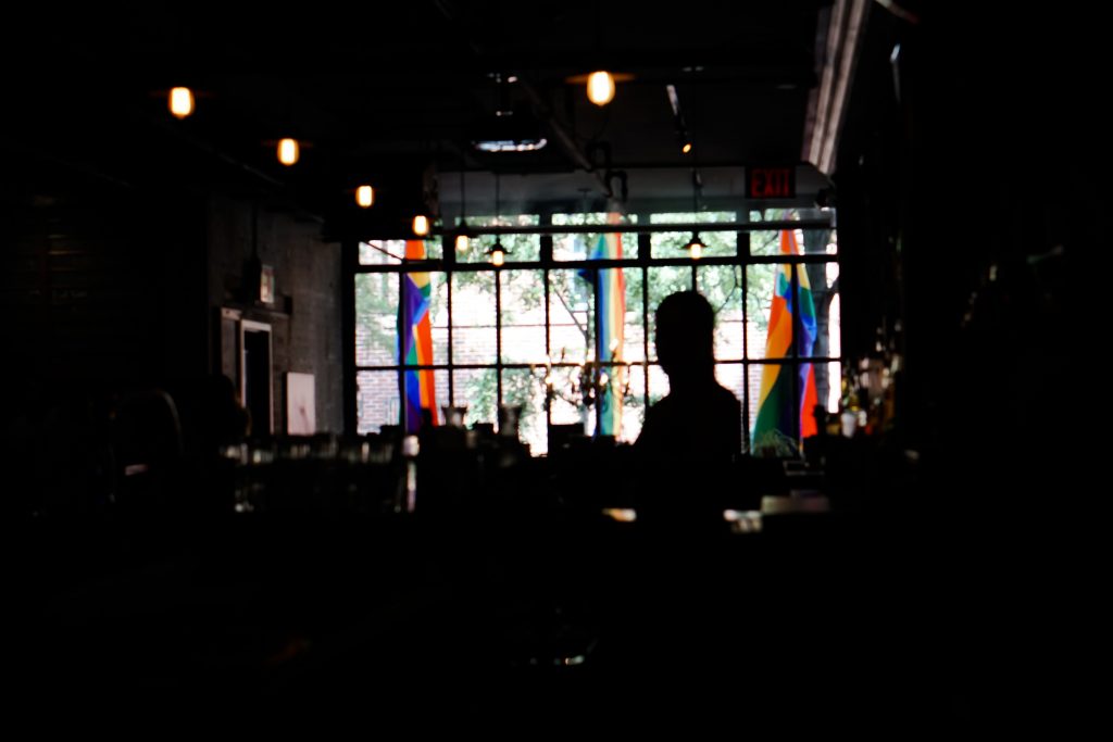 Photo shows the inside of a venue with rainbow flags displayed outside the windows