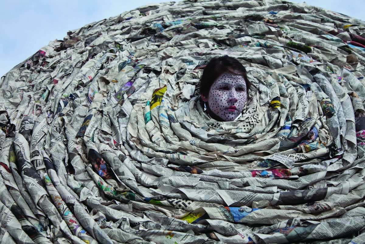 A face in the centre of a large spiral made of newspaper