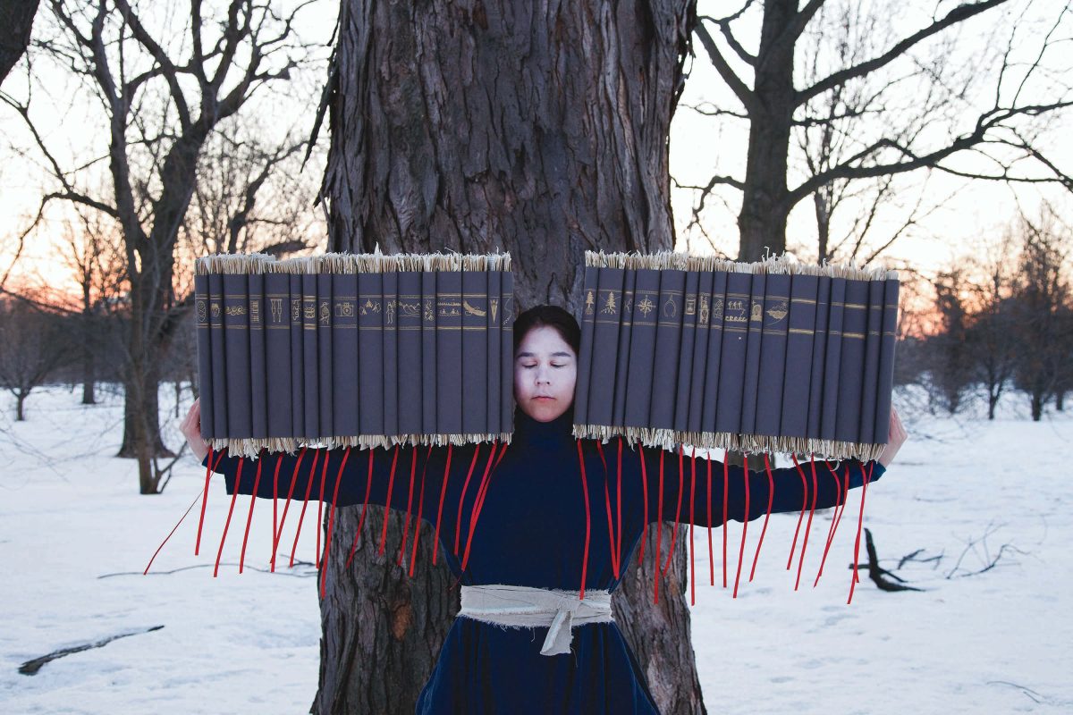 Person holds objects with string hanging down from them in front of a tree