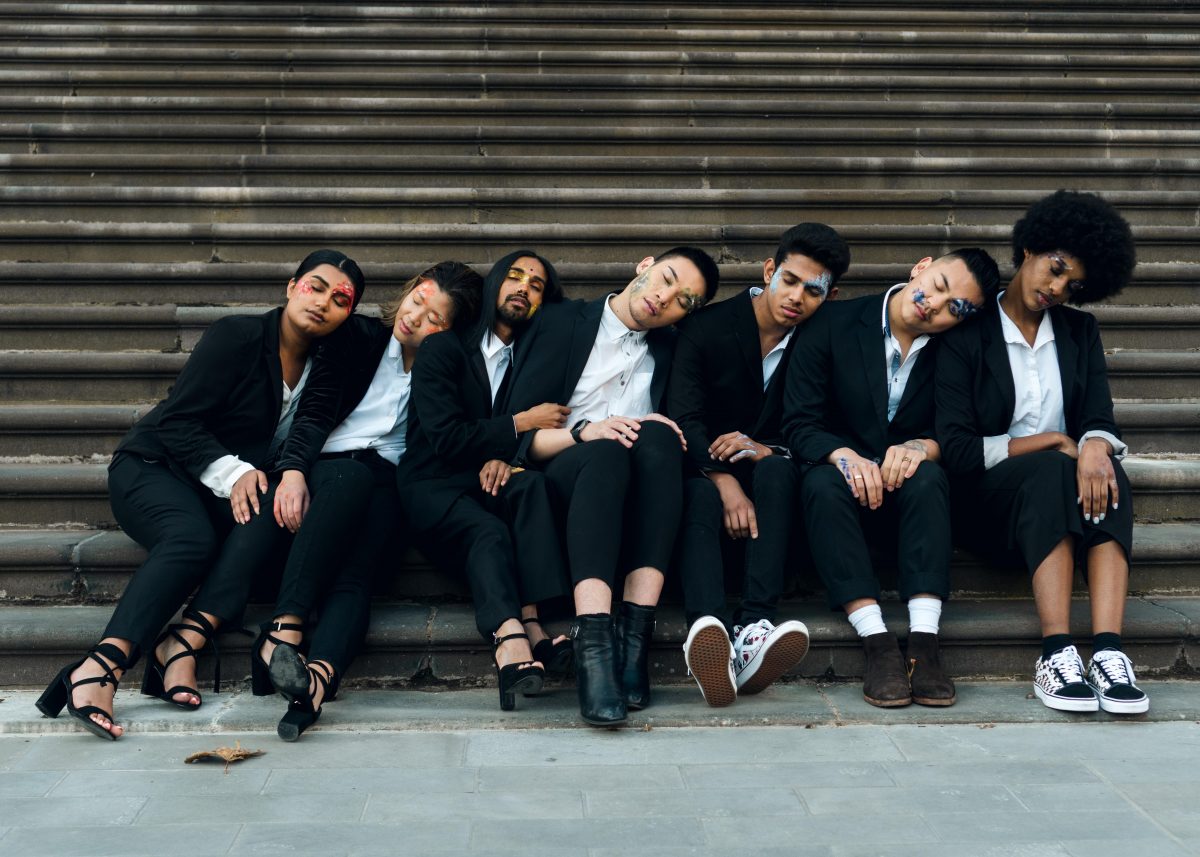 A group of Asian models sit at the bottom of a flight of steps, leaning their heads to the left