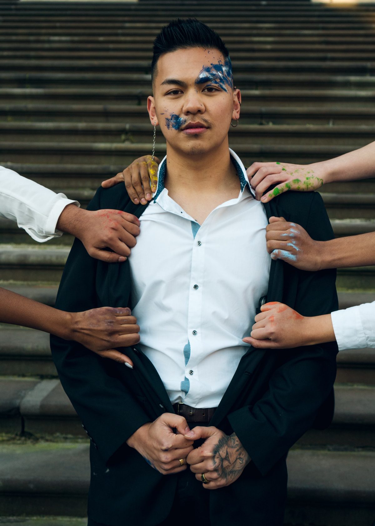 A person stands facing forward with hands pulling at his suit jacket