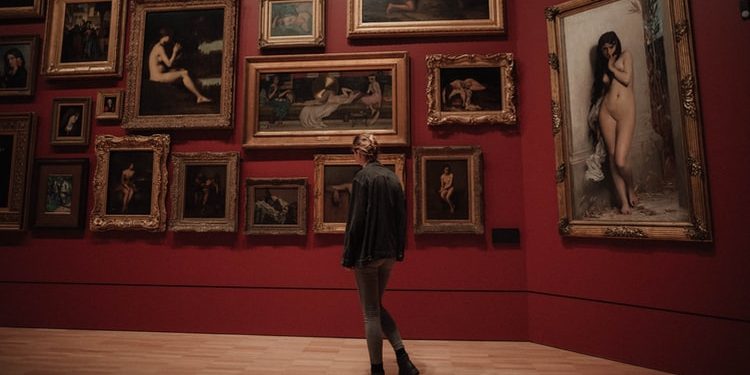 person standing in front of paintings in museum