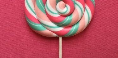 Pink and green striped lollipop on pink background