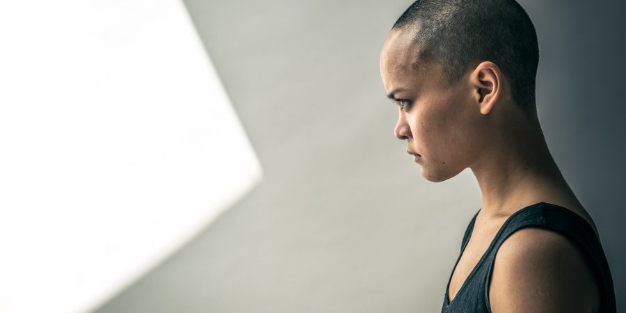 Side profile of person with shaved head wearing black tank top and looking determined