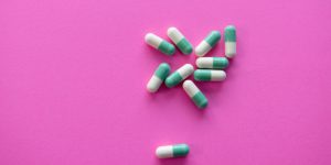 White and green pills on a bright pink background