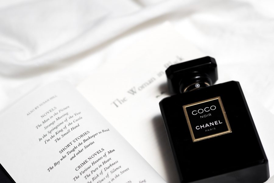 A black and gold Chanel perfume bottle next to an open book (Susan Hill's 'The Woman in Black')