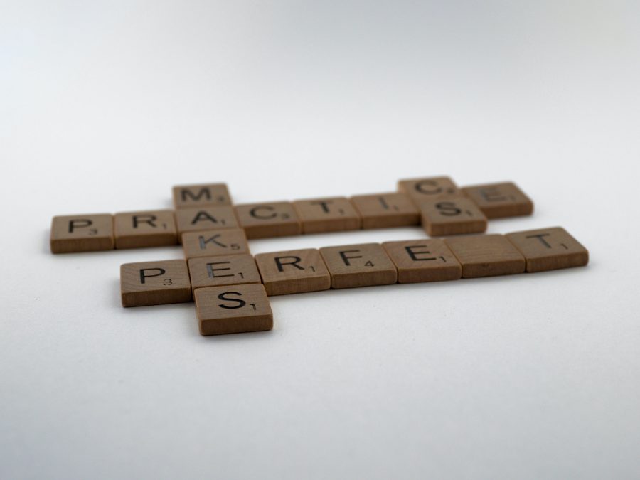 Scrabble letters spelling out 'practice makes perfect'