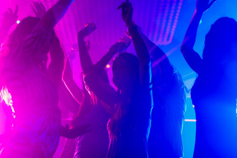 Group of people dancing in a club with magenta and deep blue lighting