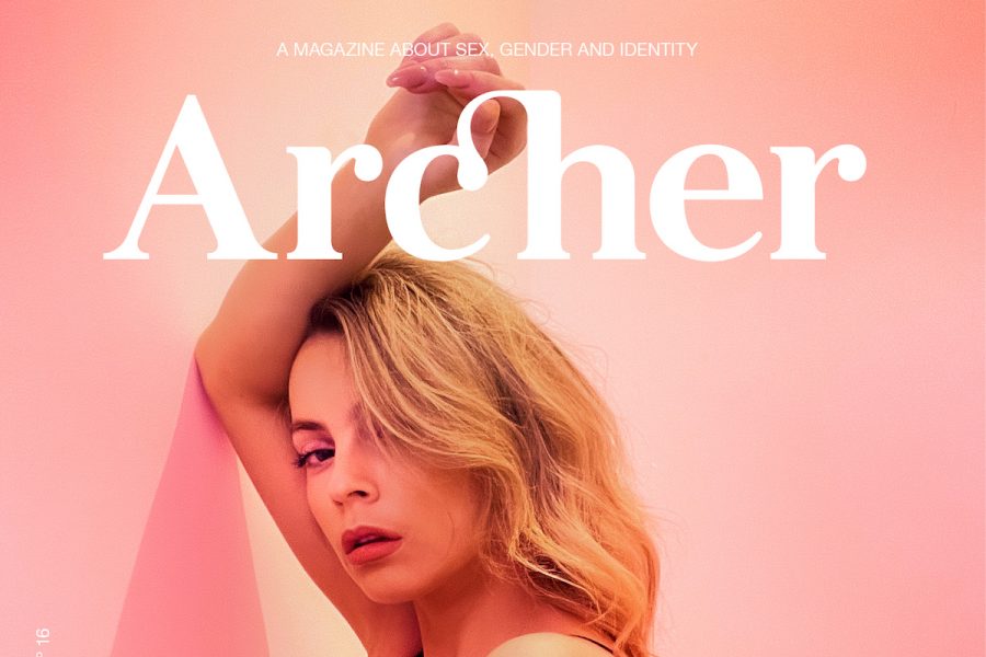 A femme person with blonde long hair is seen resting their arm up against a pink wall. In white text above their long blonde hair, it says 'Archer', indicating that this is a cover photo for the upcoming Archer issue.