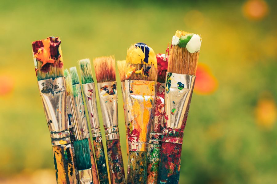 Colourful paintbrushes on green nature background