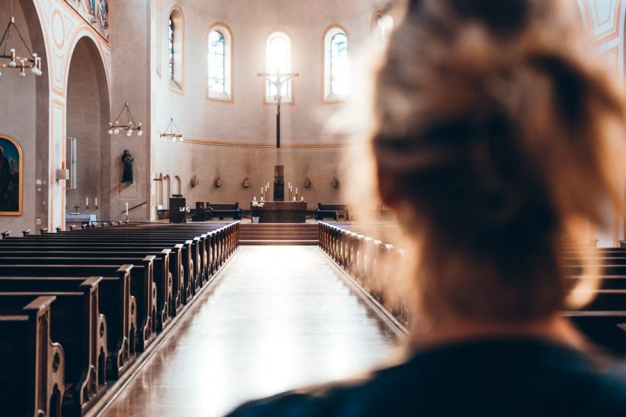 The back of a person's head. In front of them is a long aisle of a church, with pews and an alter. Embolic of this article regarding purity culture.