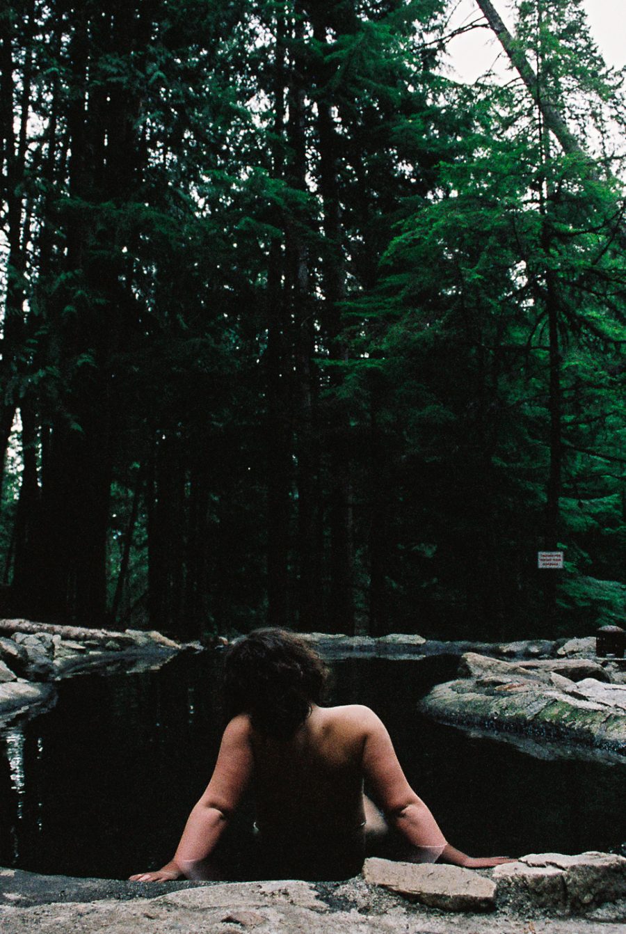 A person from behind as they relax in a hot spring.