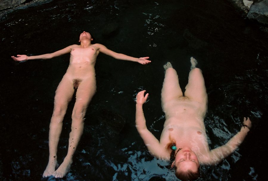 Two people floating naked in a hot spring.
