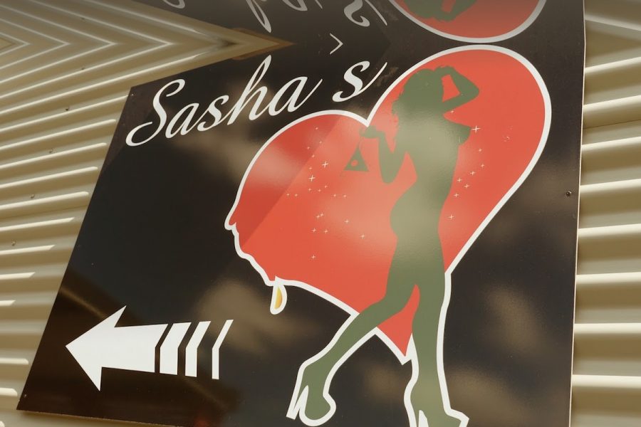 A sign for Sasha's on Cook Street with a person's silhouette in a heart.