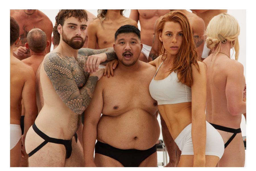 Three people face the camera. On the left, a person with short hair, tattoos and a jockstrap. In the middle, a shorter person with black briefs on. On the rigt is a person with long reddish-brown hair, wearing white undies and a crop top.
