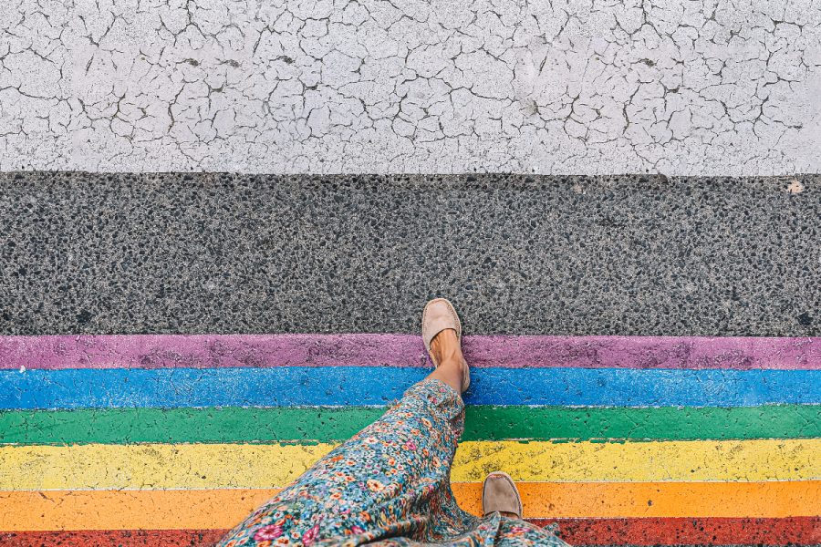 A person's feet as they walk on a rainbow crossing,