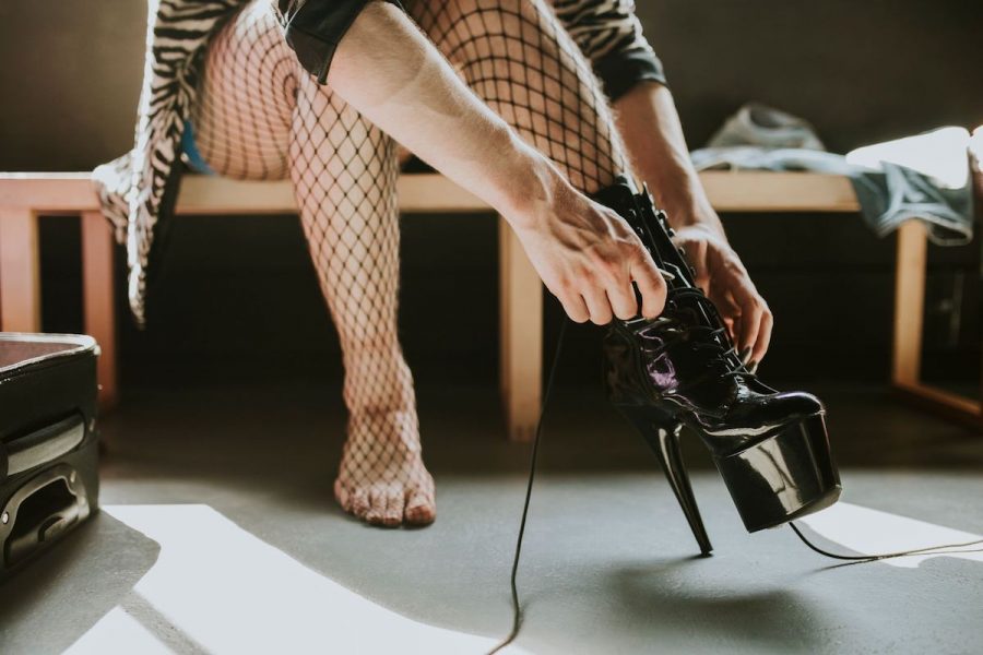 A person in fishnets putting on high heels.