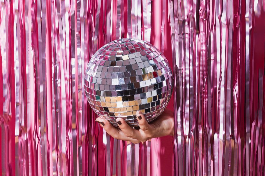 A hand emerging from pink streamers, holding a disco ball and inviting the viewer to party at Eurovision.