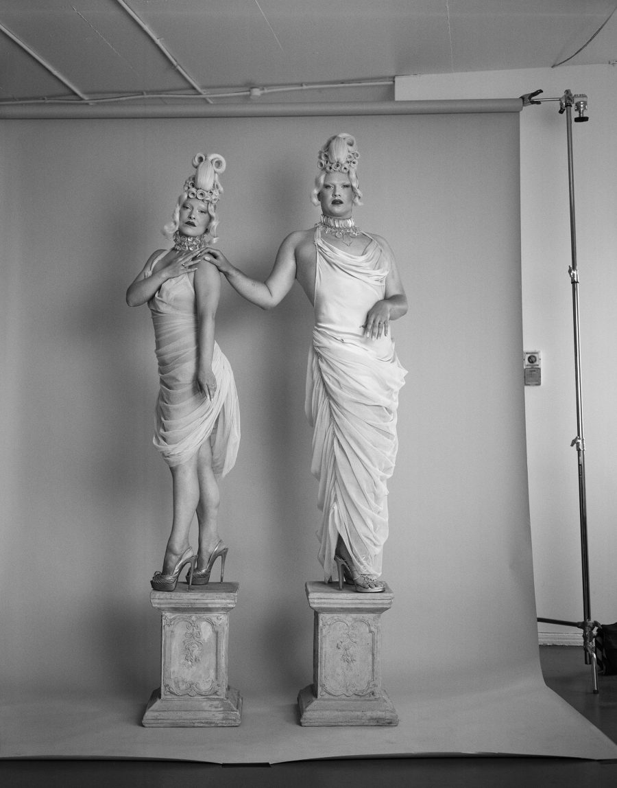 Two people posed as regal statues in black-and-white. Taken by Liz Ham.