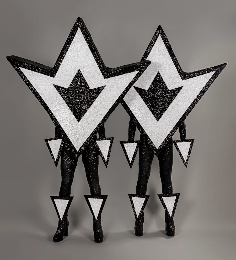 The Huxleys in geometric black and white costumes shaped like triangles or arrows.