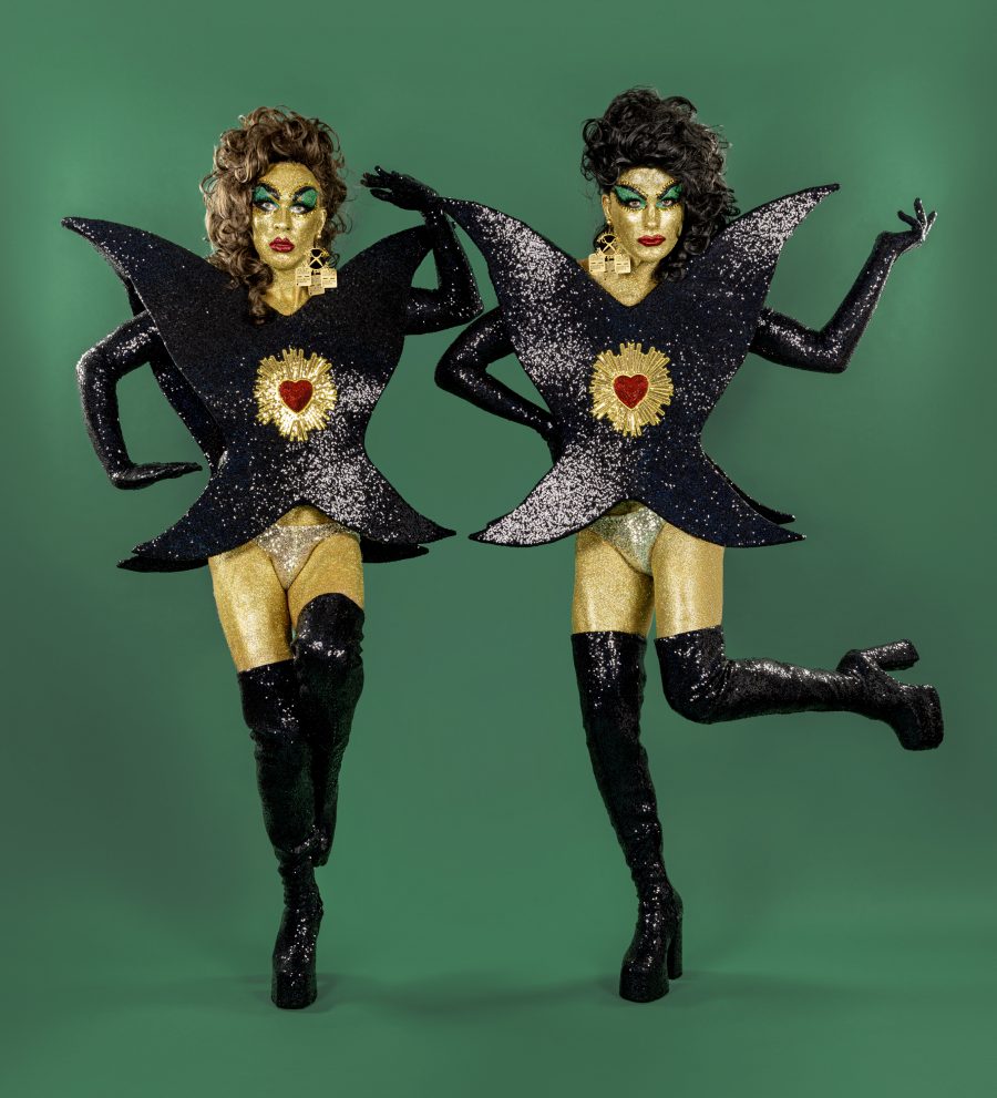 The Huxleys dancing in black and gold costumes shaped like butterflies. They have a red heart in the centre of each costume.