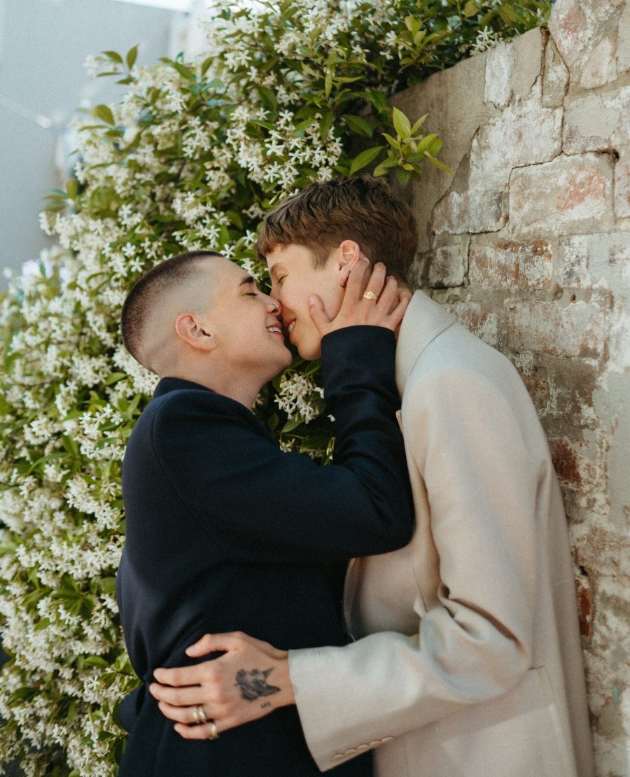 A queer couple kissing on their wedding day.