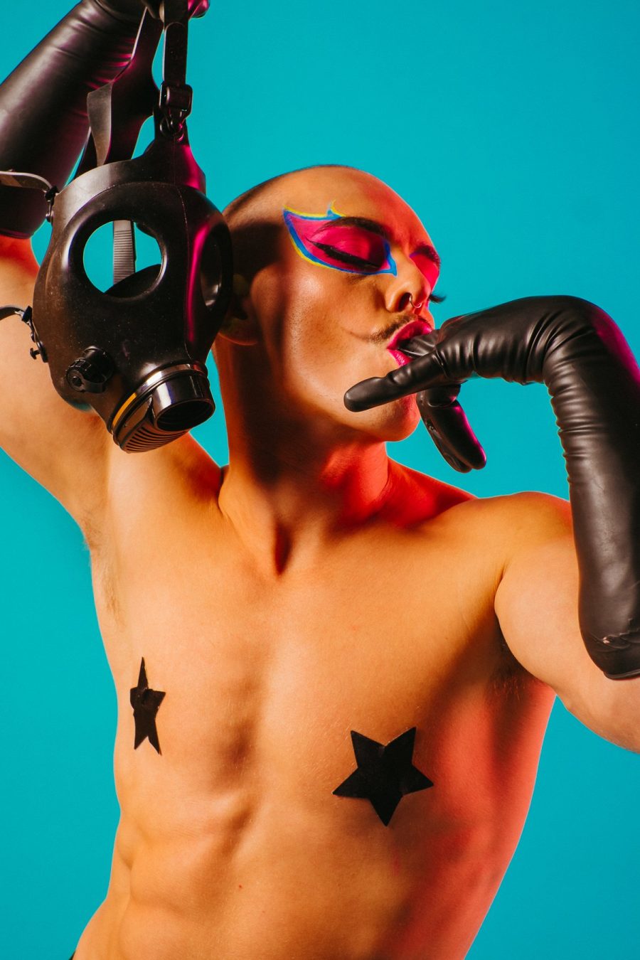 A queer performer with graphic eyeliner and star-shaped nipple pasties.