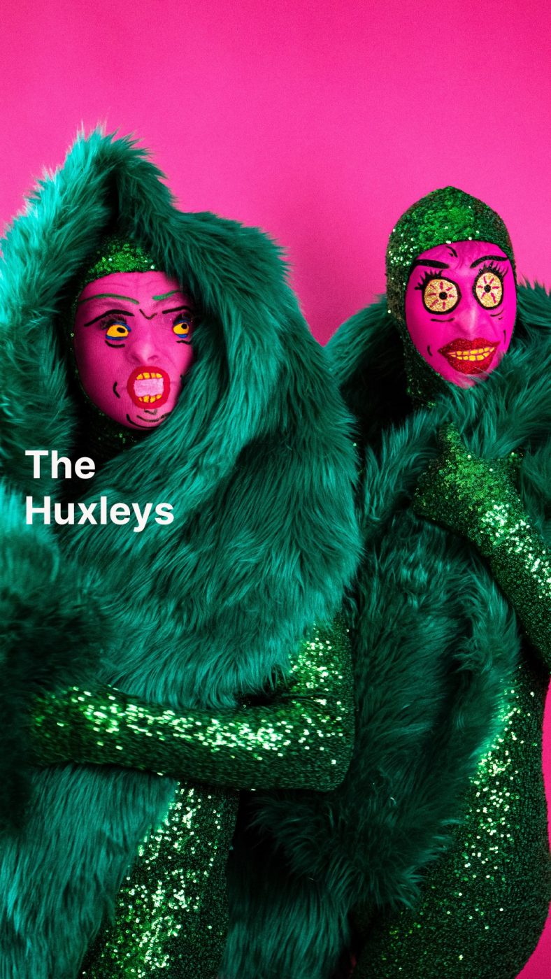 The Huxleys in green and pink costumes with cartoonish faces.