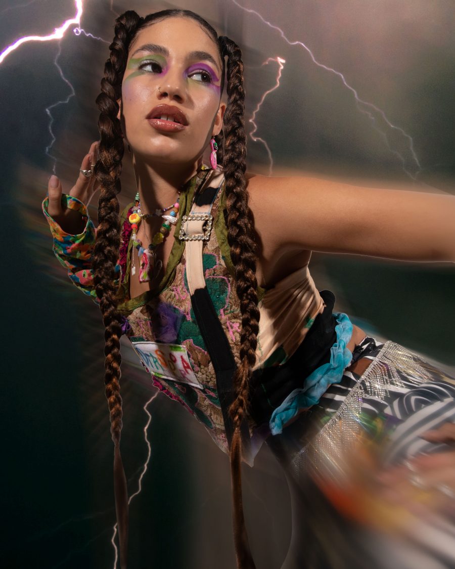 A person wearing interesting textures and accessories, with lightning in the background.