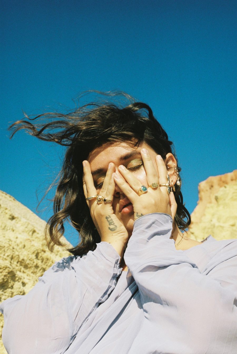 A person covering their face as their hair blows in the wind. Taken by Jade Florence.