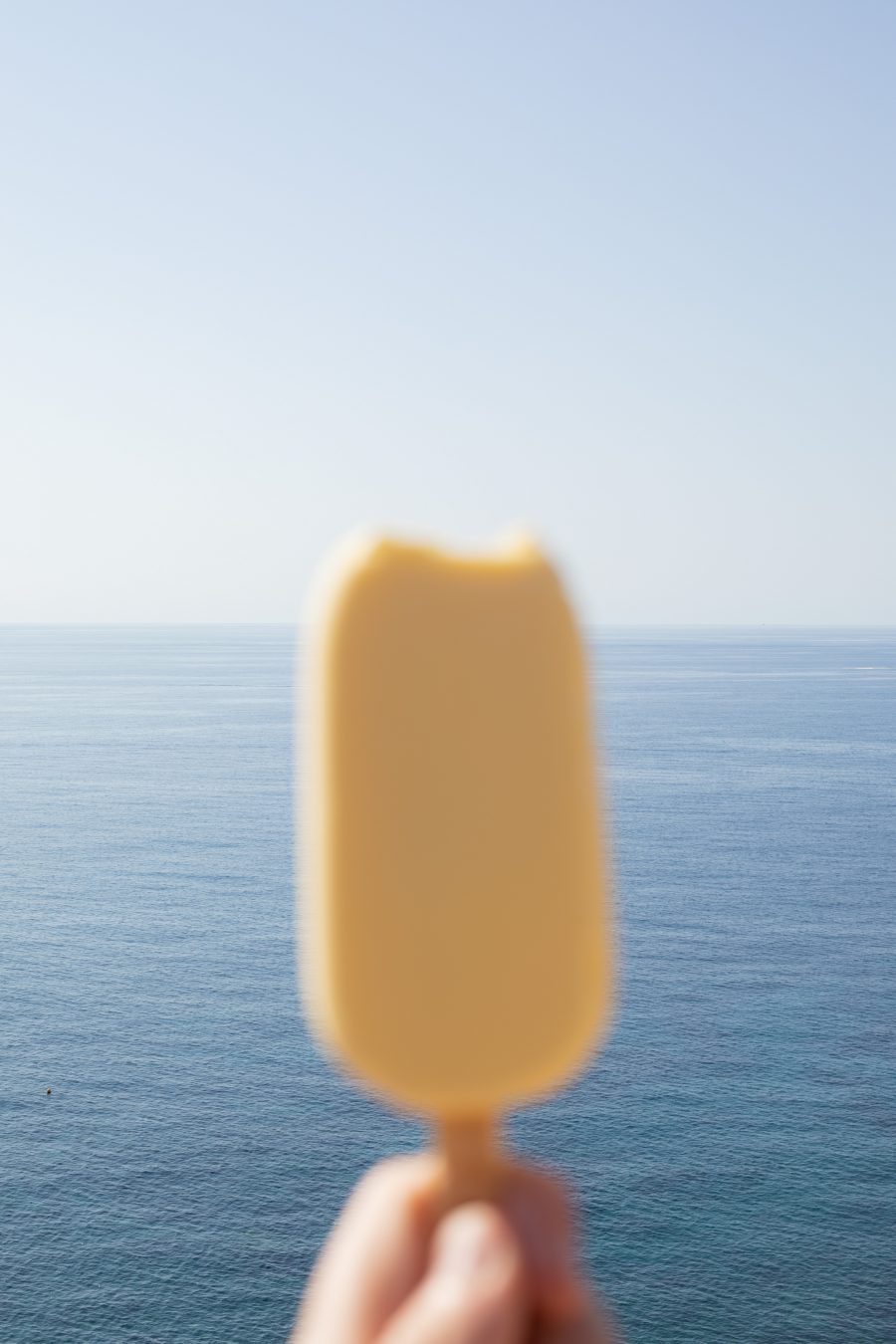 An ice cream popsicle held in front of the sea.