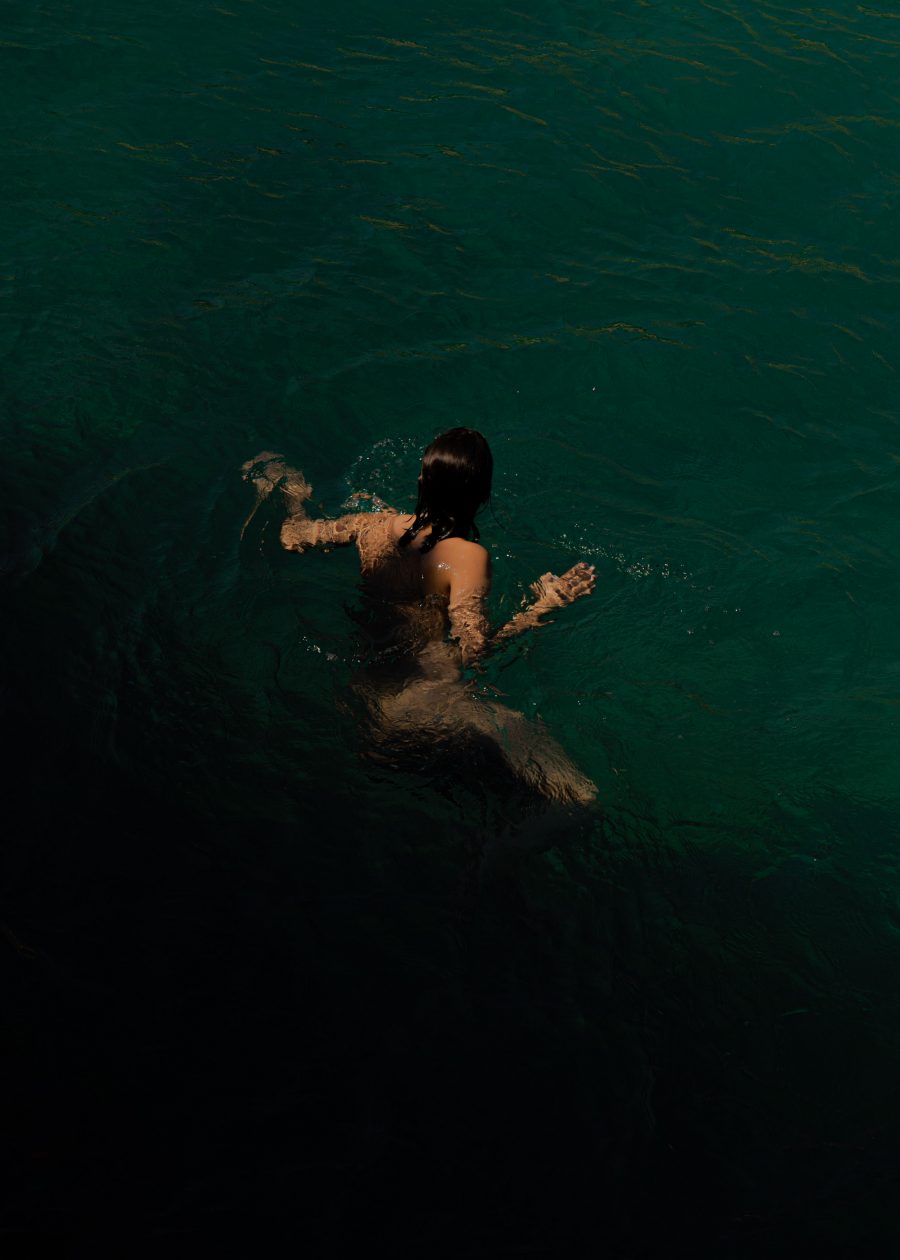 A person with long dark hair treading water.