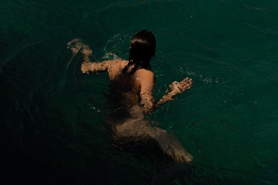 A person with long dark hair treading water.