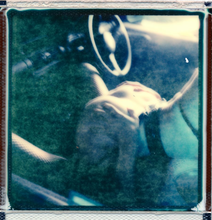 A porn still of two people fucking in a car.