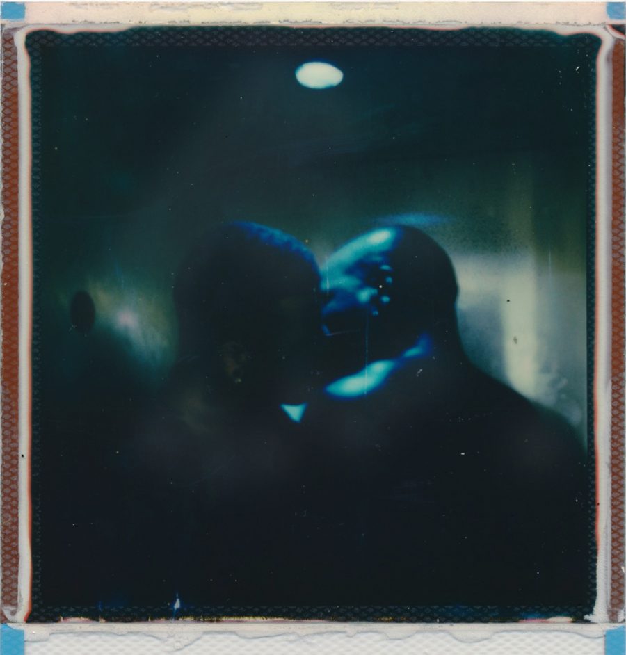 Two people kissing in blue lighting.