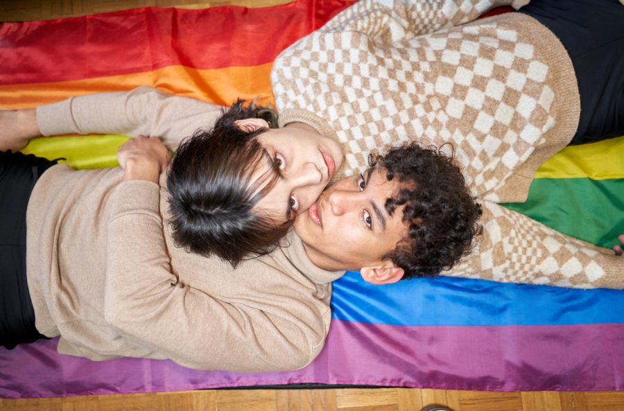 Two people laying on a queer pride flag.