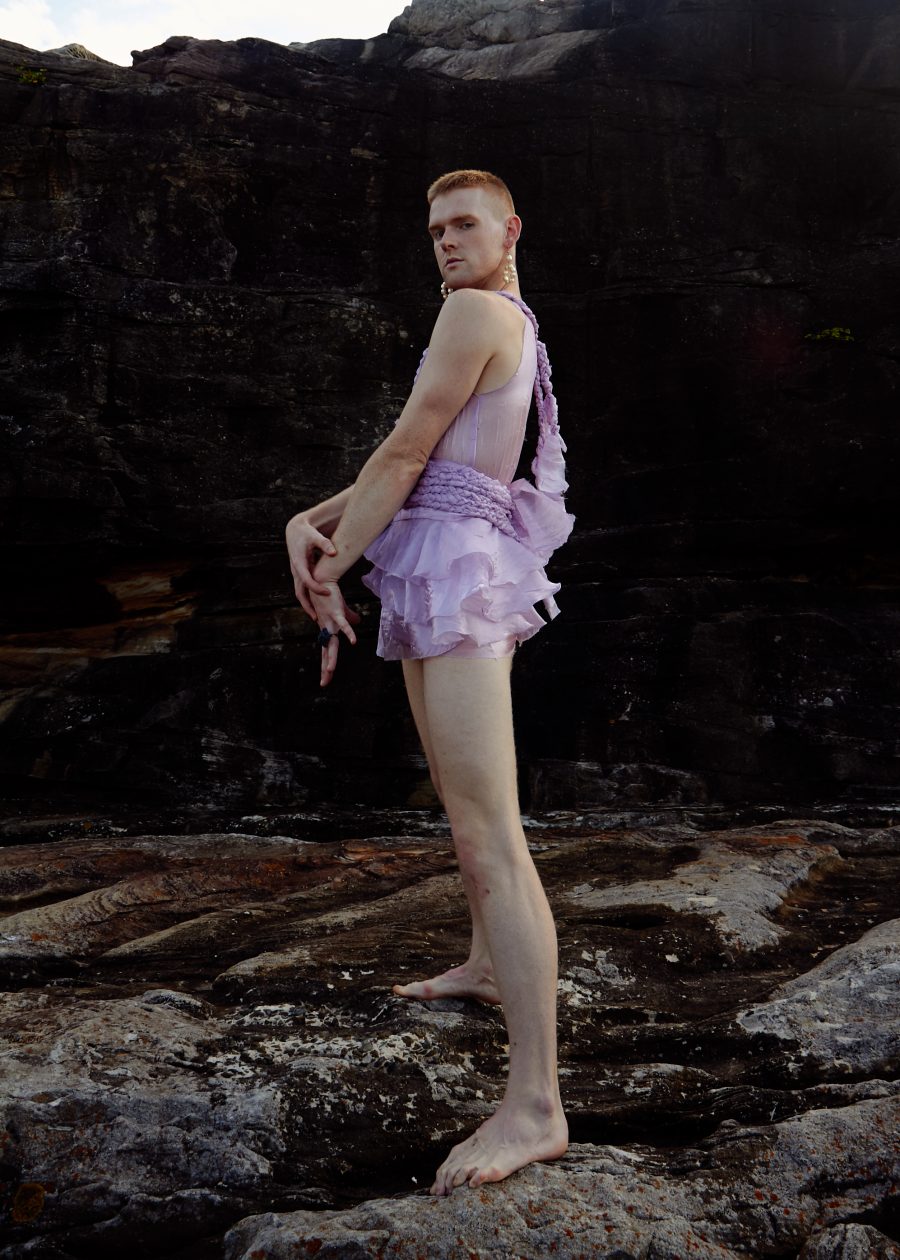 A person on some rocks in a braided garment with a short tutu.