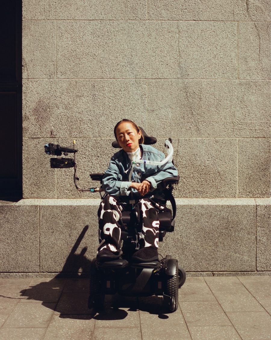 Alice Wong in her wheelchair wearing cow print pants.