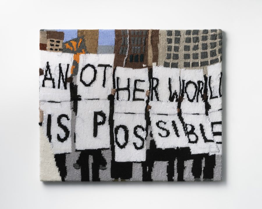 Protest textile art that says "ANOTHER WORLD IS POSSIBLE".