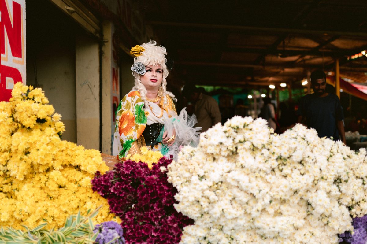 Patruni, in opulent floral drag, behind multiple flower blooms.